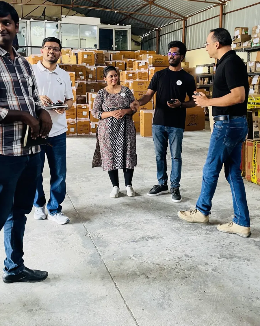 The author with PIPRA colleagues and the CEO in the customer's warehouse, talking among stacked cartons.