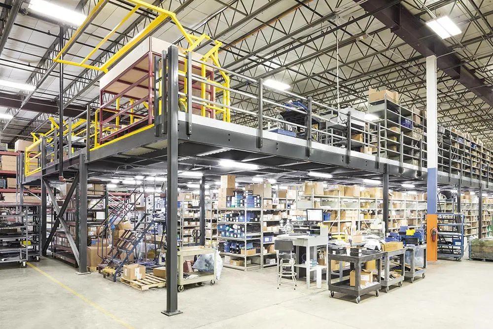 A photograph of a physical warehouse with a steel mezzanine platform above ground-level shelving.